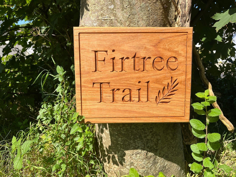 Carved oak sign in woodland setting.